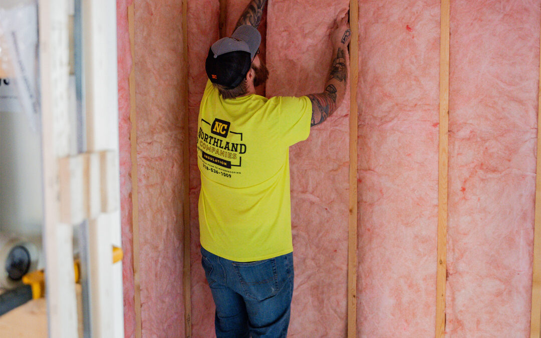 A worker is installing a pink fiberglass
