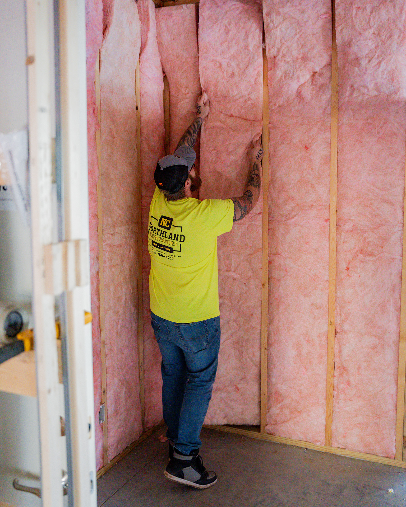 A worker is installing a pink fiberglass