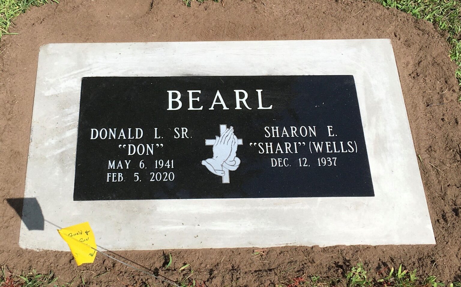 Granite grave marker set in cement within a concrete border